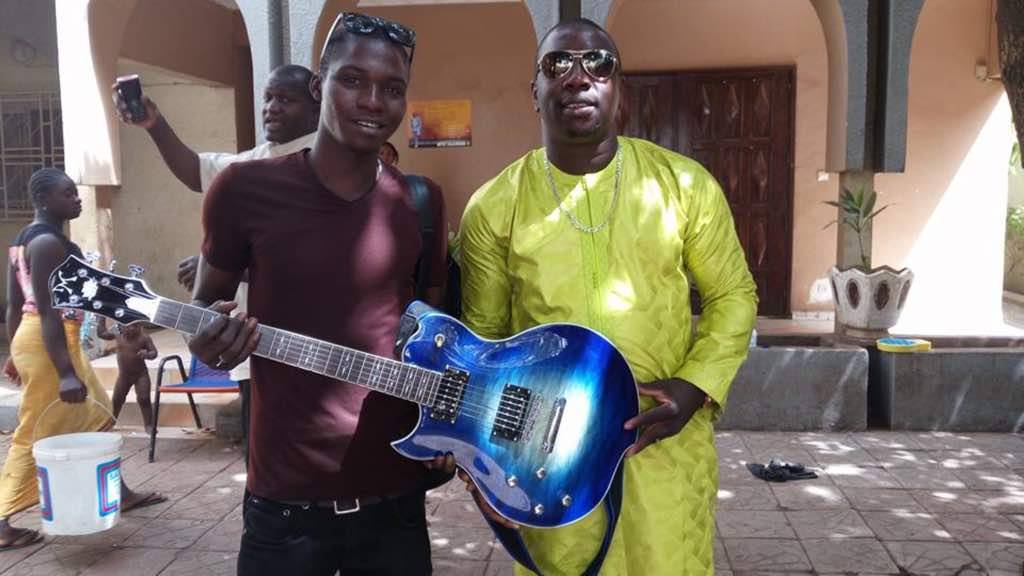 Vieux Farka Touré remet une guitare électrique pour gaucher à un jeune musicien.